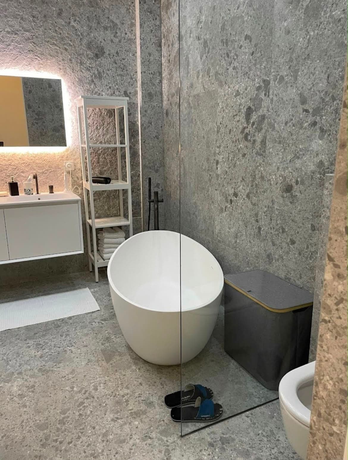 Baignoire îlot dans une salle de bain carrelée en pierre grise