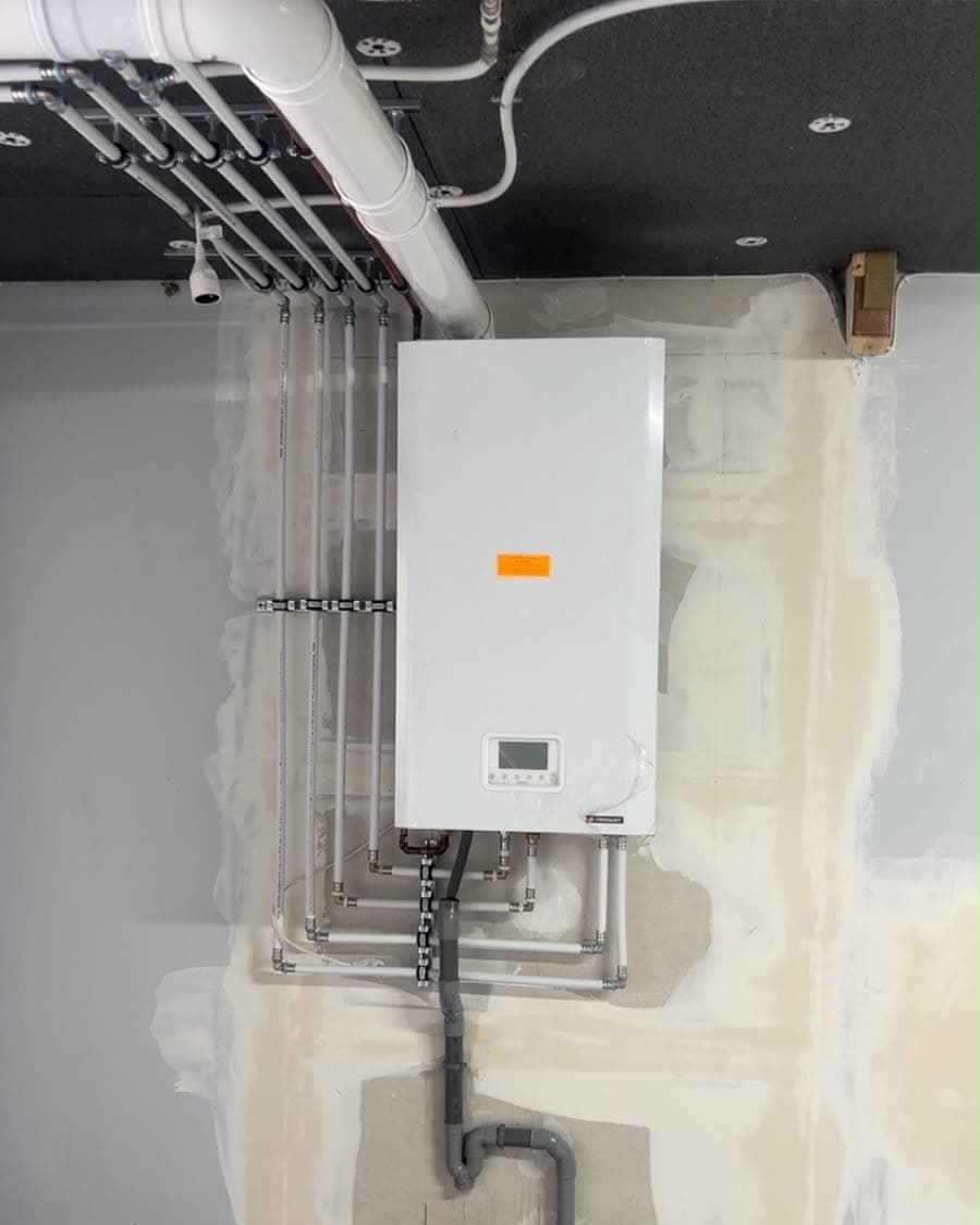 Chaudière murale gaz raccordée à ses collecteurs, réseau de distribution et évacuation, installée par HYDROBAT SOLUTIONS