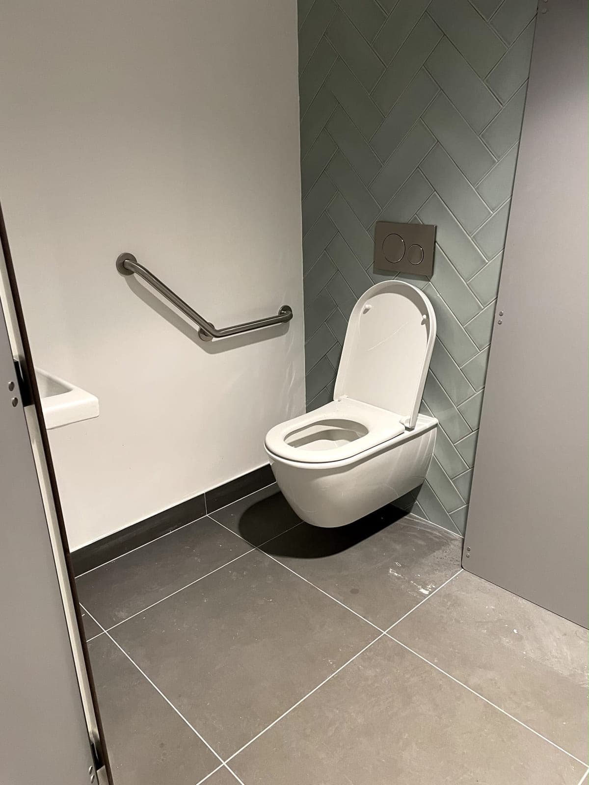 WC suspendu équipé d'une barre d'appui dans un sanitaire accessible